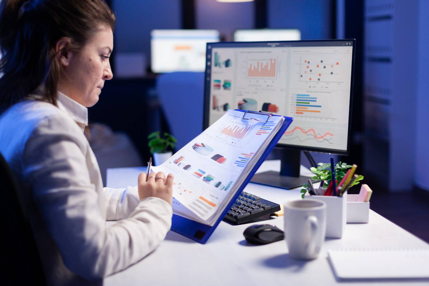 freelancer-woman-comparing-graphics-from-clipboard-with-grafics-from-computer-business-office1